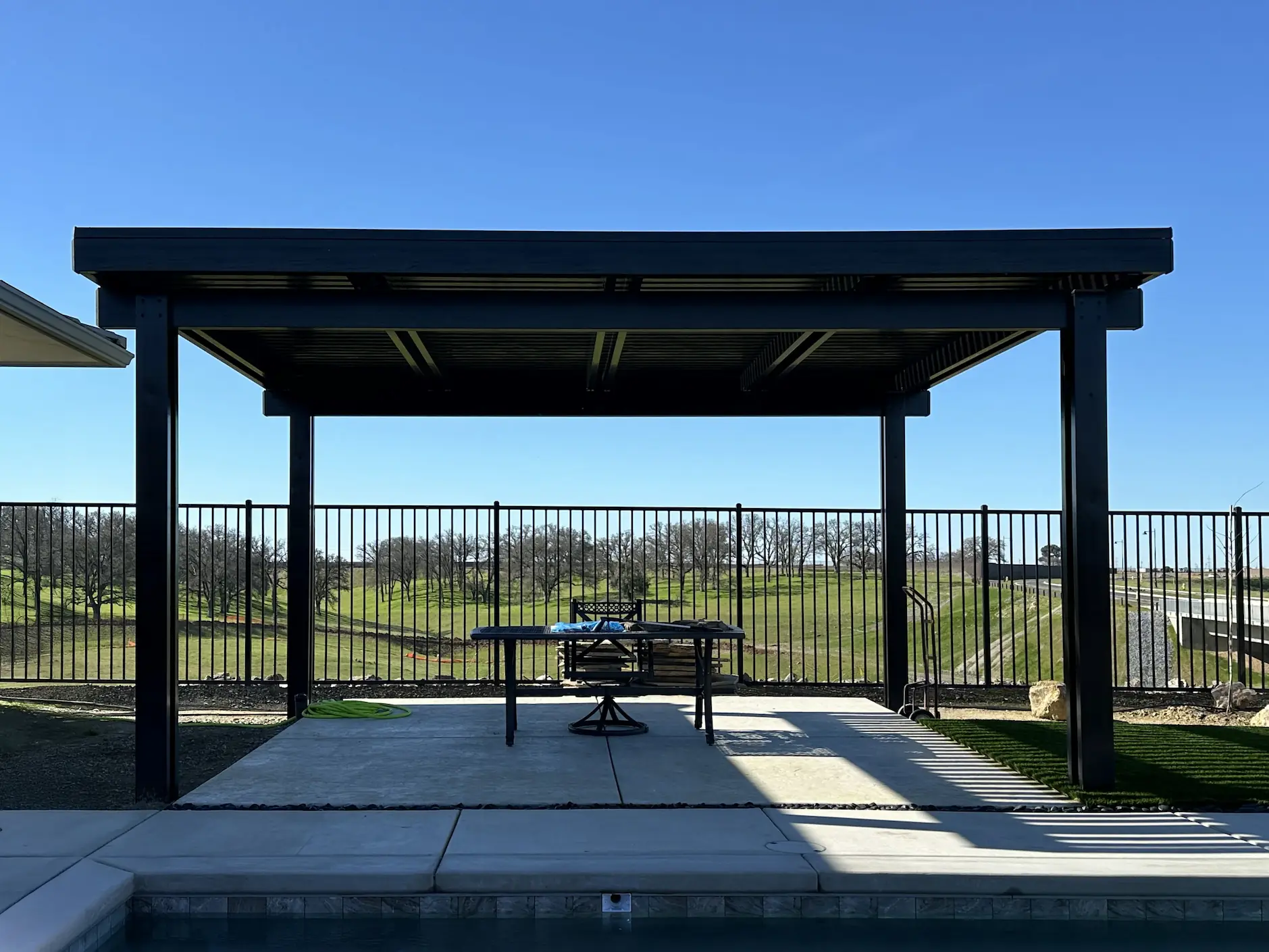 Black freestanding solid patio cover by a pool deck in Roseville, CA by DCI Patios