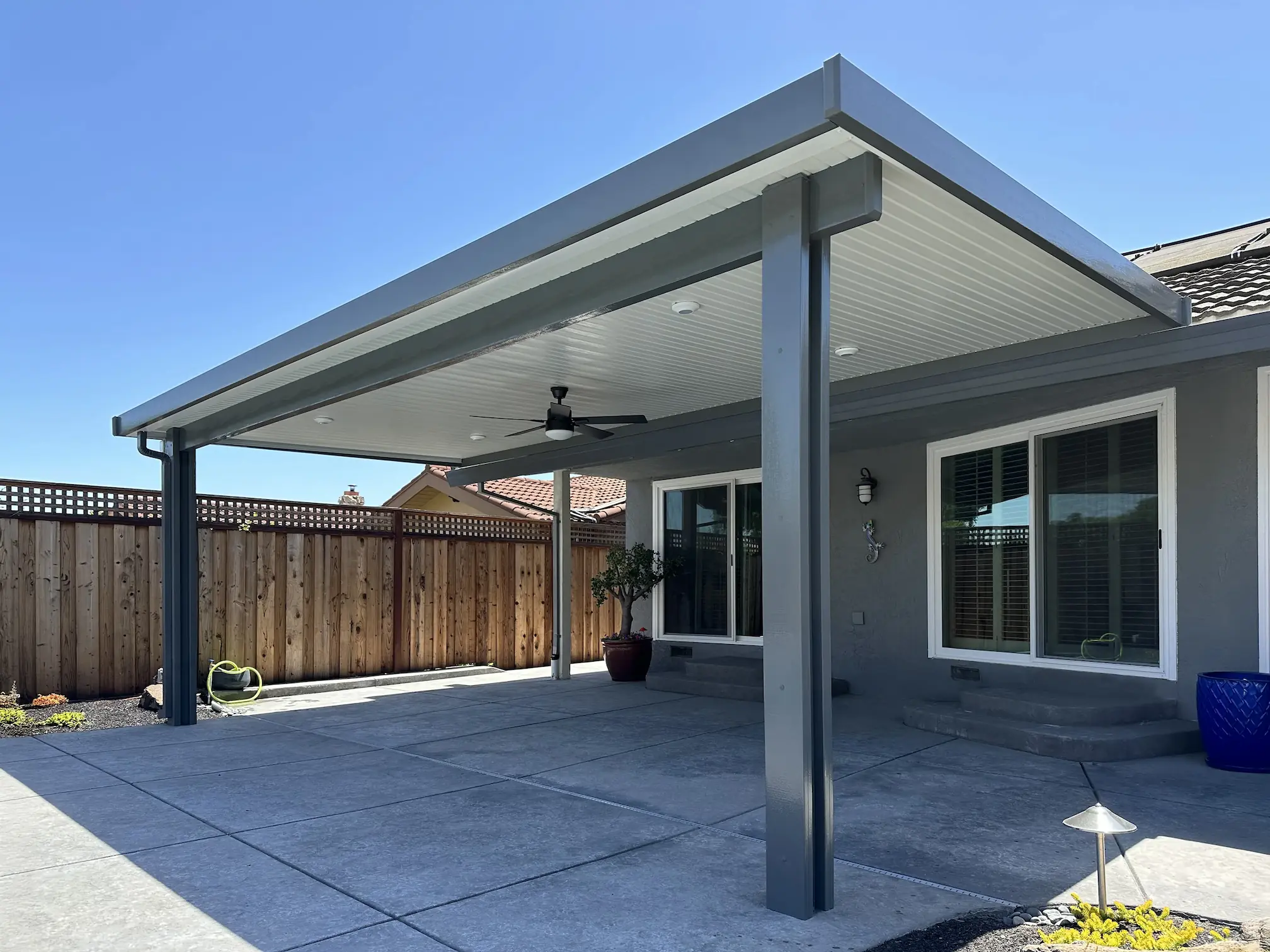 Gray attached solid patio cover over large concrete patio in Folsom by DCI Patios